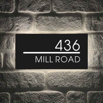 Custom LED house letterbox address sign displaying number 436 and Mill Road on a wall at night.