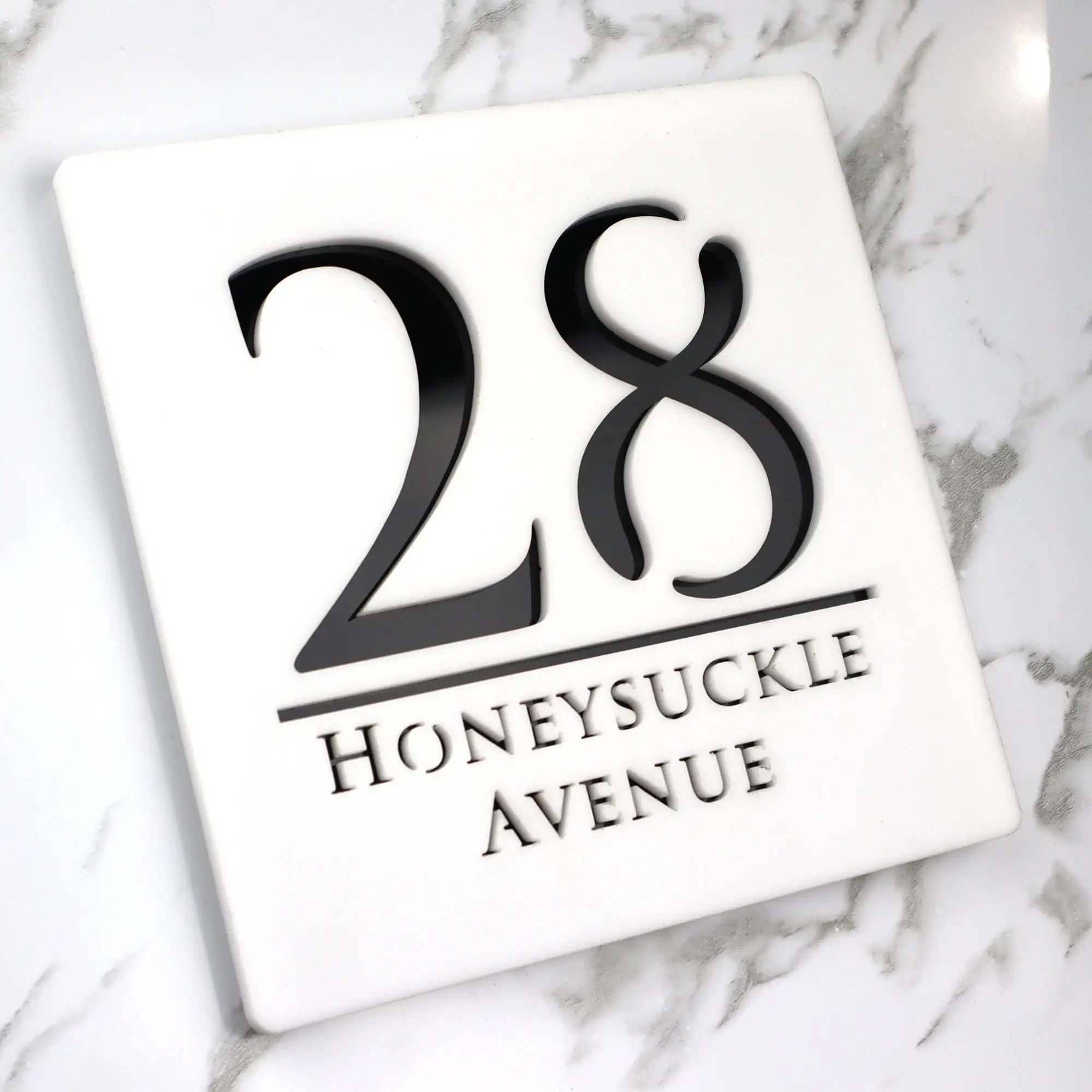 Square custom acrylic house sign displaying number 28 and Honeysuckle Avenue in black text on white background