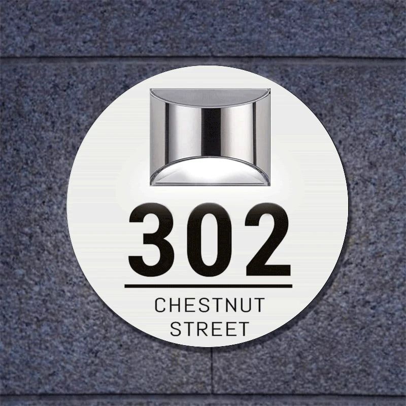 Circular solar-powered acrylic house sign with custom etched address and modern silver light fixture above
