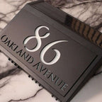 Modern solar-powered custom acrylic house sign with laser-etched address numbers and text on black panel