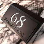Modern solar-powered custom acrylic house sign with address number and street name on black background