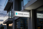 Aurora Assets sign on a modern building exterior with a cloudy sky.